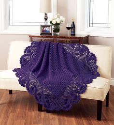 a blue crocheted blanket sitting on top of a white couch