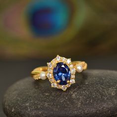 a close up of a ring on a rock with a peacock feather in the background