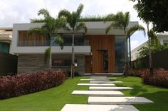 a modern house with stone steps leading up to the front door and trees in the yard