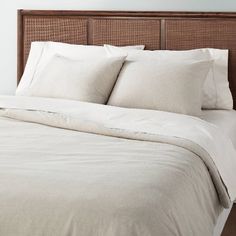 an unmade bed with white linens and pillows on top of the headboard