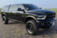 a large black truck parked on top of a gravel road