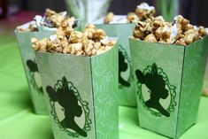 three green boxes filled with popcorn sitting on top of a table