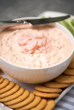 a white bowl filled with shrimp dip surrounded by crackers