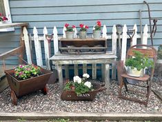 an assortment of potted plants sitting in front of a white picket - fenced house