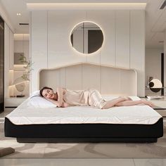 a woman laying on top of a bed in a room with white walls and flooring