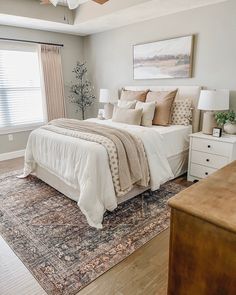 a bedroom with a bed, dressers and windows in it's center area