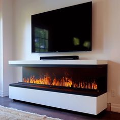 a flat screen tv mounted on top of a white wall next to a fire place