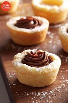 chocolate frosted pastry sitting on top of a wooden table next to other pastries