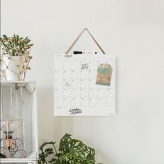 a calendar hanging on a wall next to a potted plant