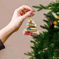 a hand holding a christmas tree ornament with books on it