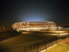 an illuminated stadium at night with stairs leading up to it