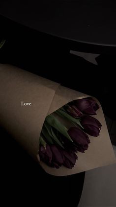 a bouquet of tulips wrapped in brown paper with the word love written on it