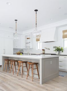 a kitchen with white cabinets and wooden stools next to an island in the middle