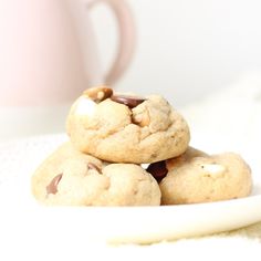 three chocolate chip cookies stacked on top of each other in front of a pink mug