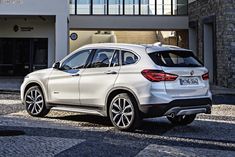 a white bmw suv parked in front of a building