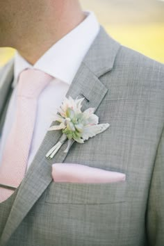 a man in a gray suit with a pink tie and flower boutonniere