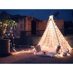 a teepee is lit up with fairy lights