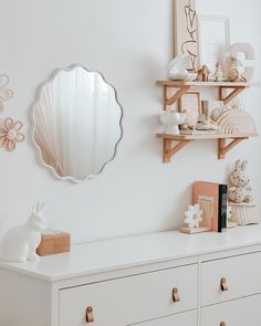 a white dresser topped with lots of drawers and a mirror on the wall above it