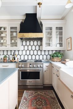 a kitchen with white cabinets and an area rug on the floor in front of the stove