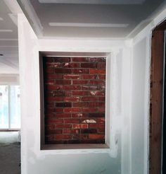 an empty room with a brick wall and window in the middle, being painted white