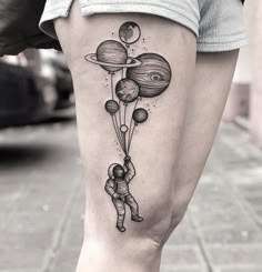 a woman's thigh with an astronaut tattoo on it and balloons floating in the air