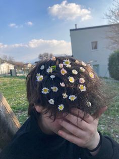 a man with flowers in his hair covering his face