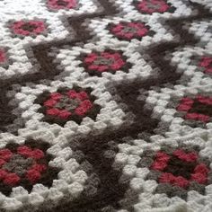 a crocheted rug with red and gray flowers on it is laying on the floor