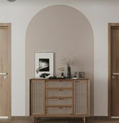 an empty room with two doors and a sideboard in the center, next to a vase on top of a wooden cabinet