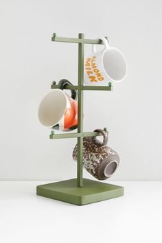 three cups are stacked on a stand with two mugs hanging from it's sides