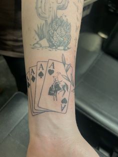 a person with a tattoo on their arm holding playing cards