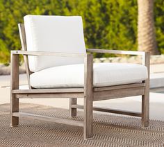 a white chair sitting on top of a rug next to a pool and palm trees