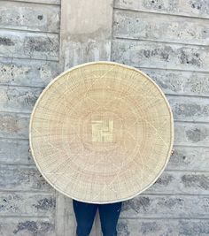 a person standing in front of a brick wall holding a large woven basket over their head