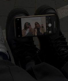 a person taking a selfie with their cell phone while wearing black sneakers and jeans