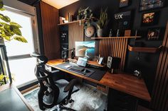 a desk with a computer on top of it in front of a window and some plants