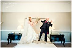 a bride and groom posing for a photo on the bed in their hotel room with two nightstands