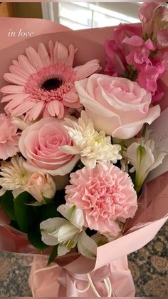 a bouquet of pink and white flowers sitting on top of a table