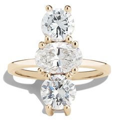 three stone engagement ring in yellow gold with two round diamonds on each side and an oval diamond