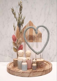 a wooden tray topped with figurines on top of a white table next to a heart