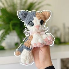 a hand holding a small crocheted cat toy