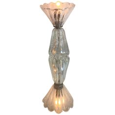 a clear glass vase with a light on it's side and the base is turned upside down