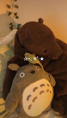 two stuffed animals laying next to each other on a bed