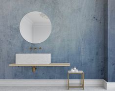 a bathroom with blue walls and a white sink under a round mirror on the wall