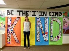 a woman standing in front of a bulletin board with the word kind written on it