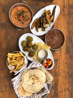 a table topped with plates of food and bowls of sauces on top of it