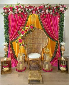 a decorated stage with pink and yellow drapes, gold lanterns and flowers on it