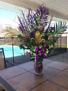 a vase filled with lots of purple flowers on top of a tile floor next to a swimming pool