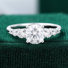 an engagement ring with three stones on it sitting on top of a green velvet box