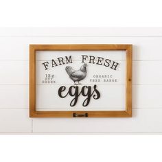 a sign that says farm fresh eggs on the side of a white wall next to a wooden frame