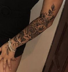 a woman with a rose tattoo on her arm and wrist is holding out her hand