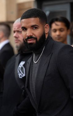 a man with a beard standing in front of other men wearing black suits and ties